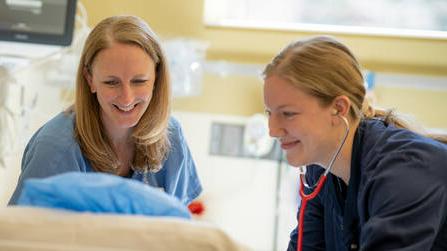 两个护士在病床上看着并听着他们的病人